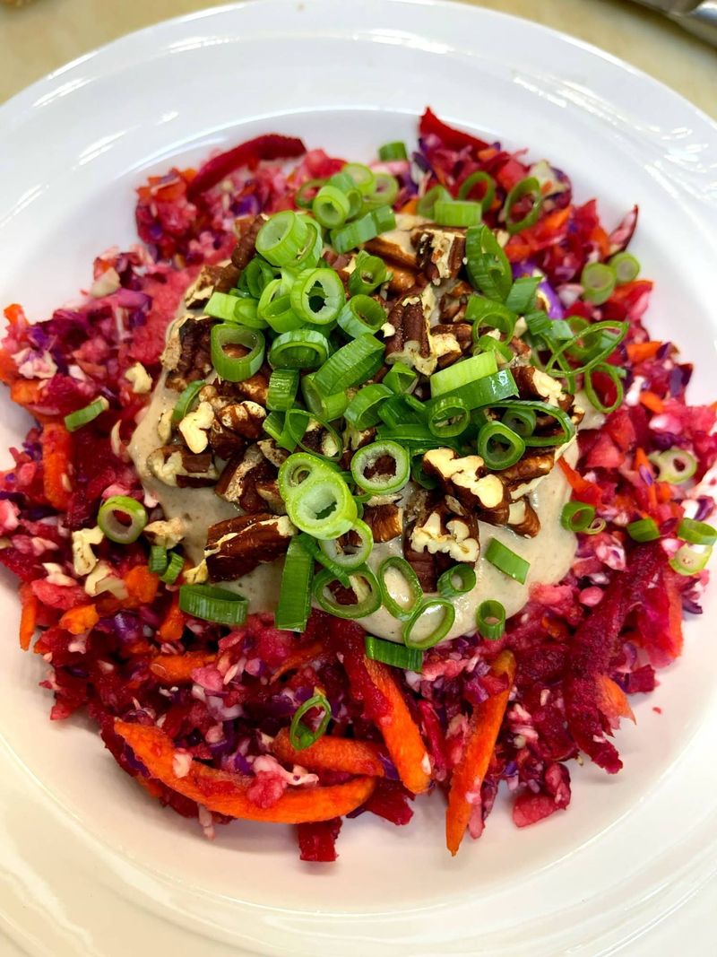 Rainbow slaw of beet, cabbage and carrot topped with a creamy dressing, pecans and green onion